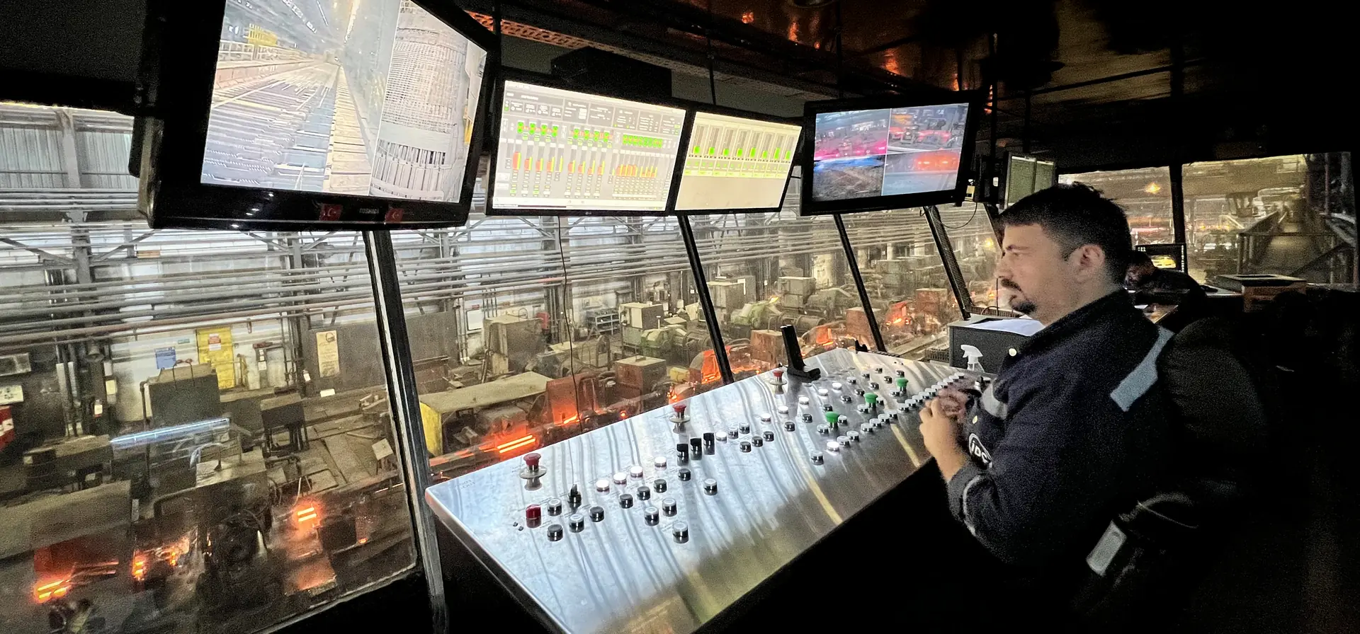 Operator at a rolling mill control pulpit with Adeptek HMI screens